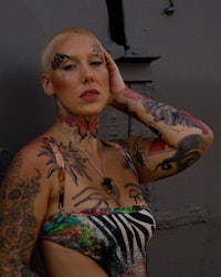 a woman with tattoos leaning against a wall