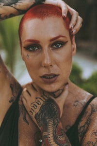 a woman with red hair and tattoos posing