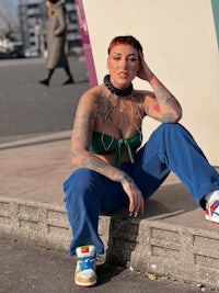 a woman with tattoos sitting on a curb