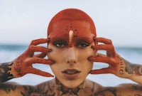a woman with red hair and tattoos on her face